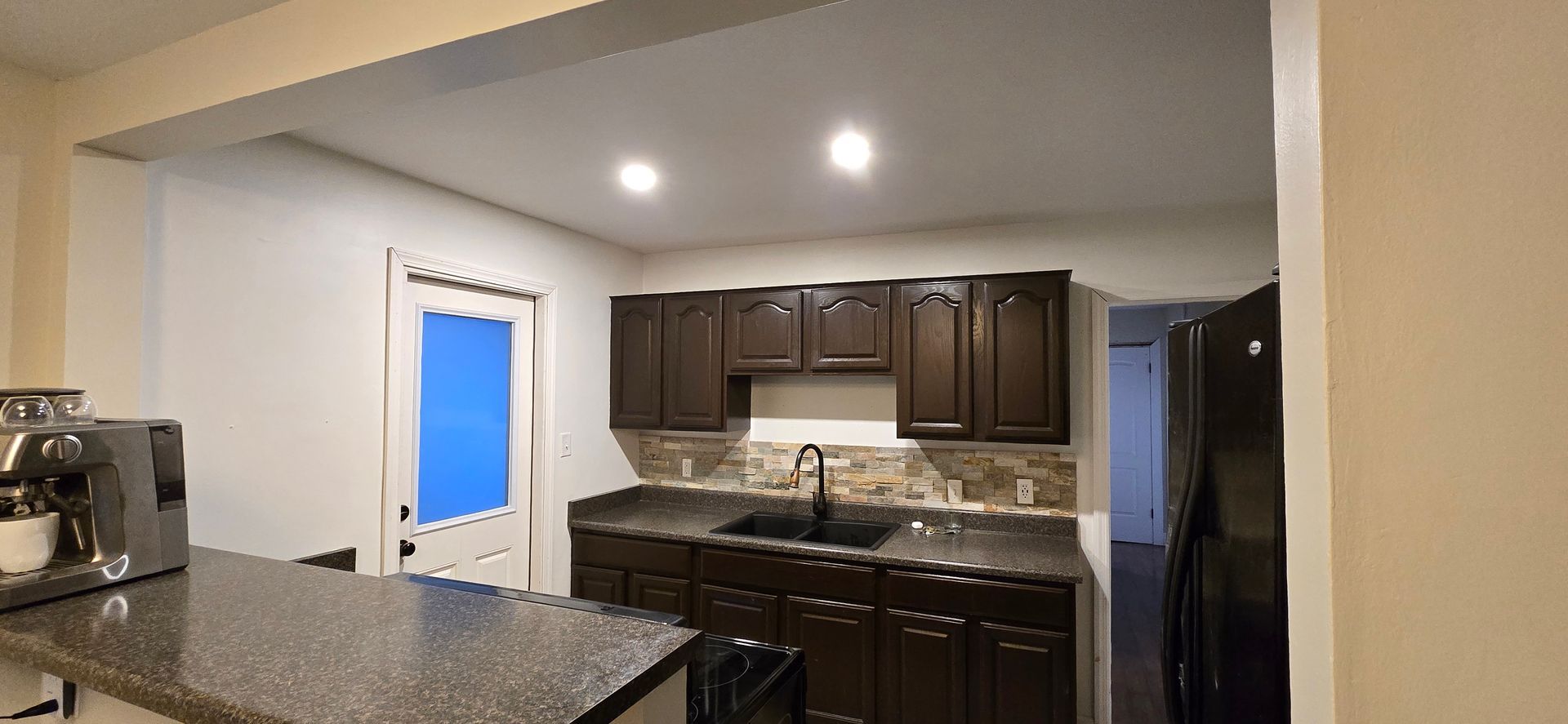 Kitchen with dark wood cabinets, granite countertops, recessed lights, and a window over the sink