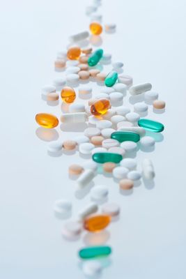 Scattered white, orange, and teal pills on a light background