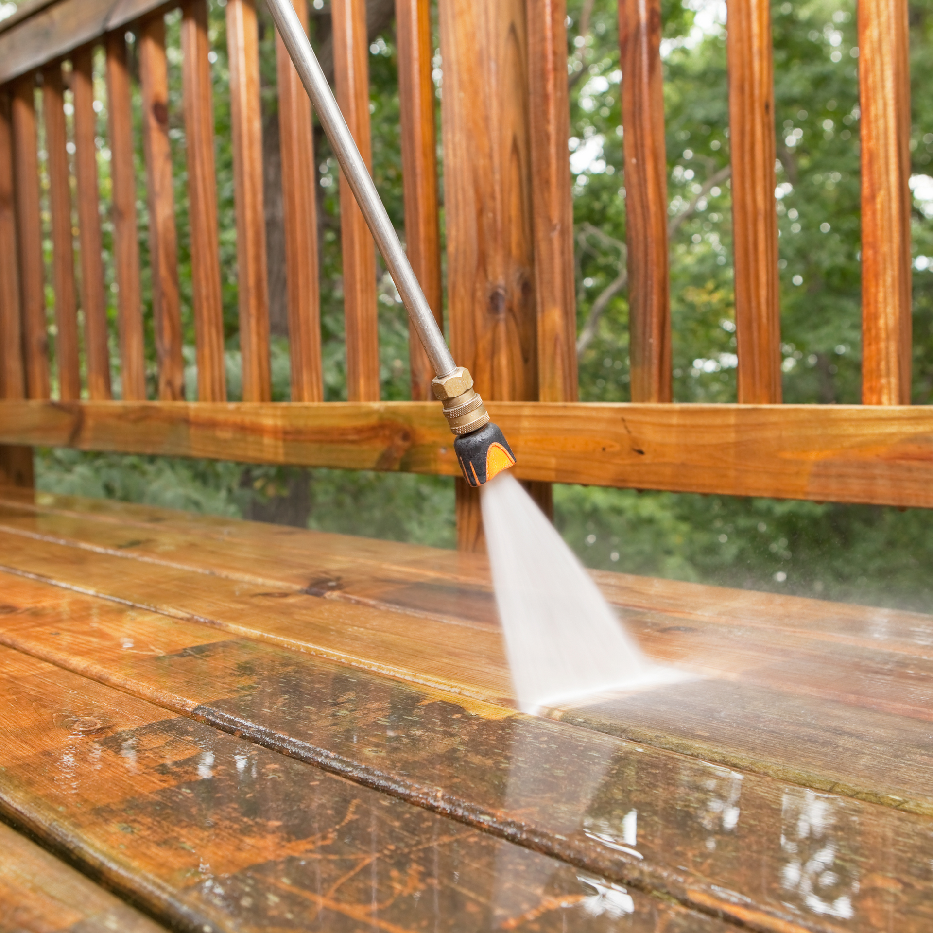 Power washing wooden deck, water spraying onto surface.