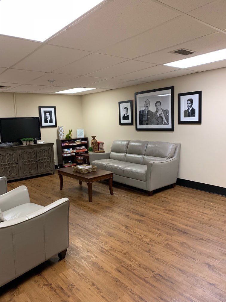 A living room with a couch , chairs , and a coffee table.