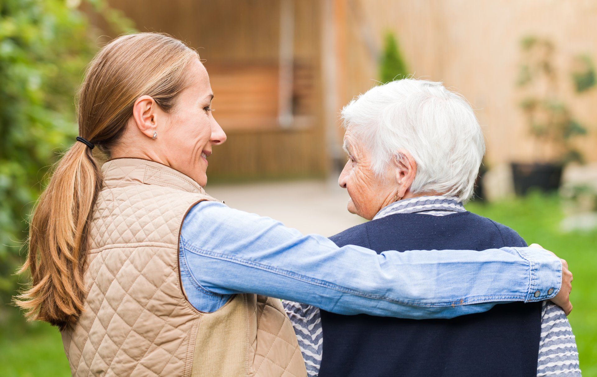 A woman is hugging an older woman in a wheelchair.