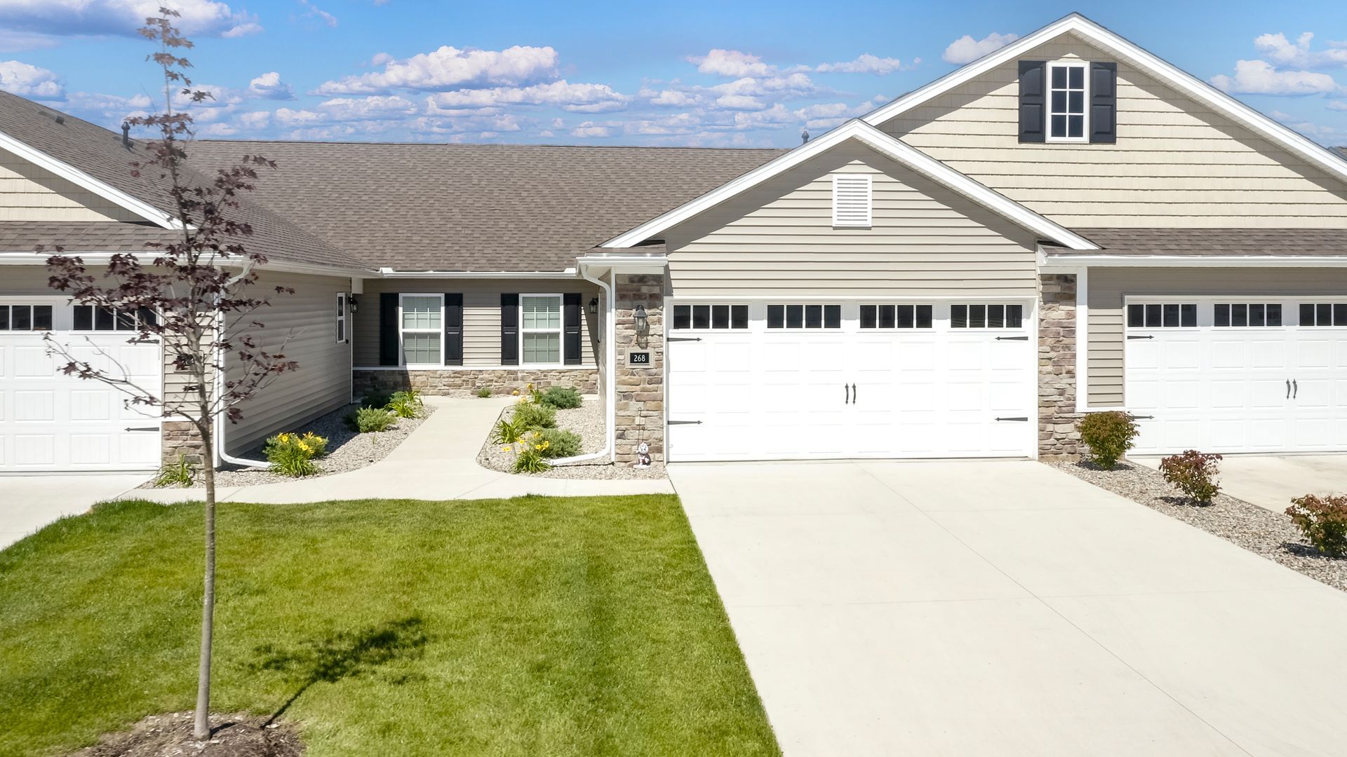Townhouse exteriors with light siding, white garage doors, and green lawn.