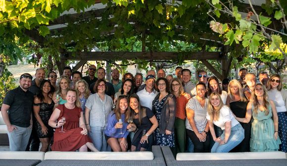 A large group of people are posing for a picture under a tree.