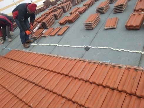 Due uomini stanno lavorando su un tetto con tegole rosse