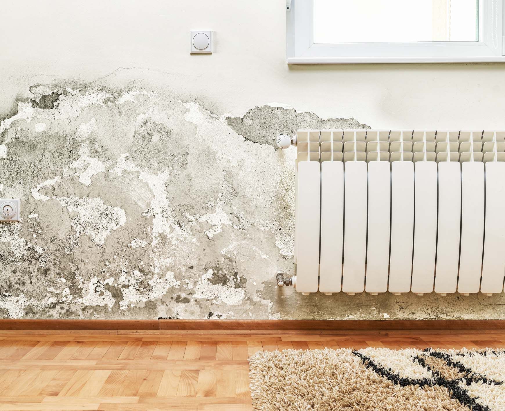 Una stanza con un termosifone e un muro sporco