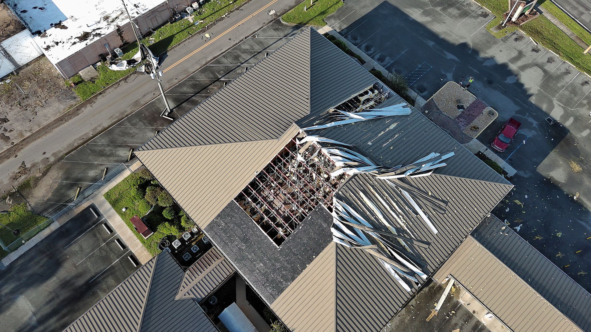 An aerial view of a building with a roof that has been damaged by a tornado.