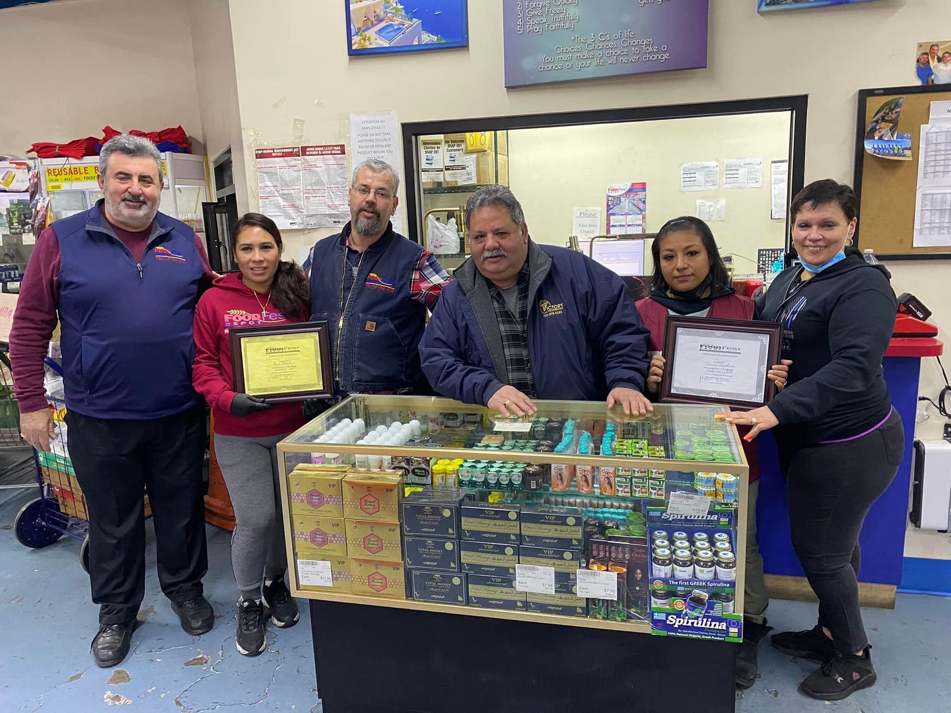 A group of people are standing around a counter in a store holding certificates.