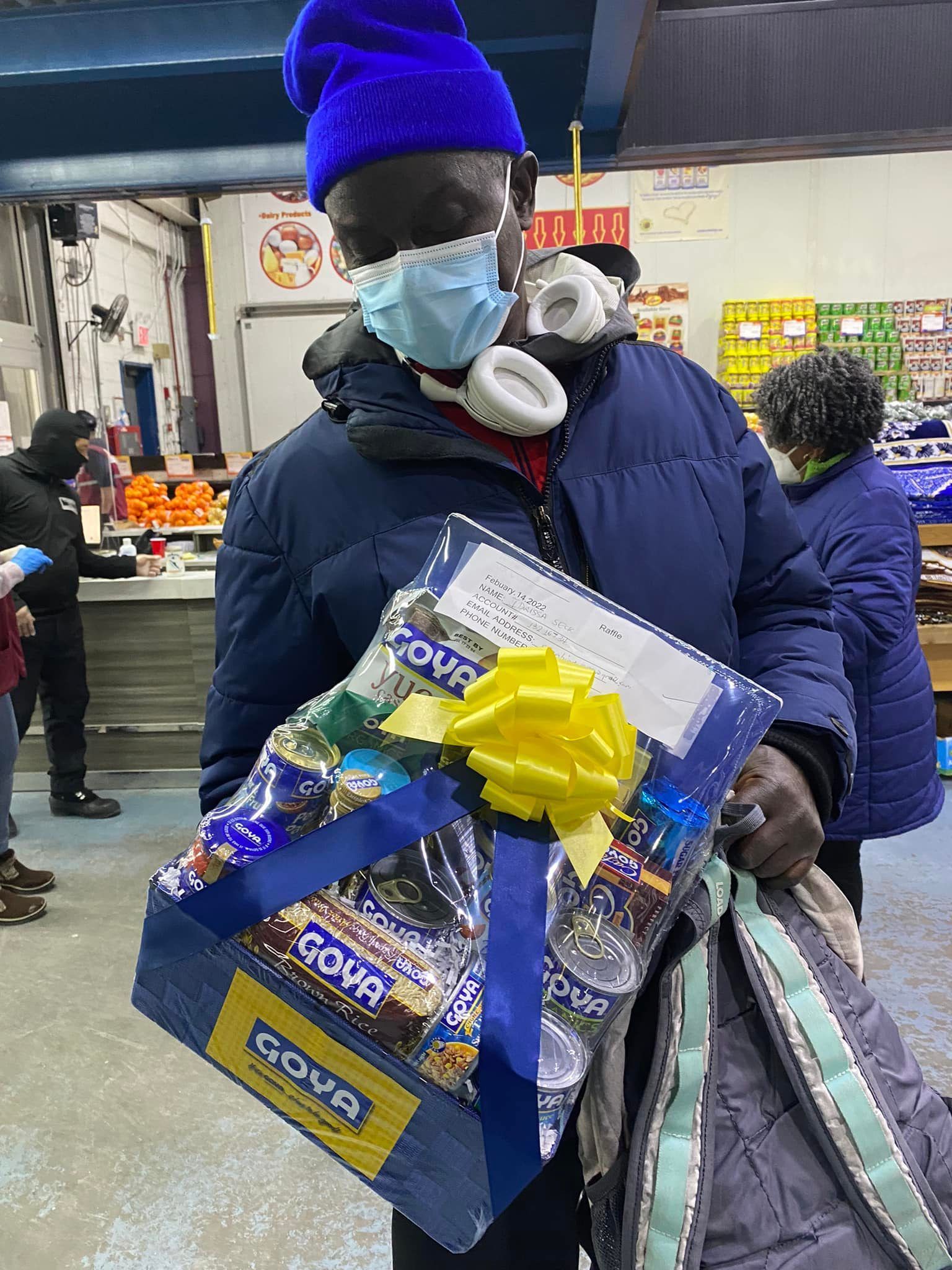 A man wearing a mask is holding a box of goods.