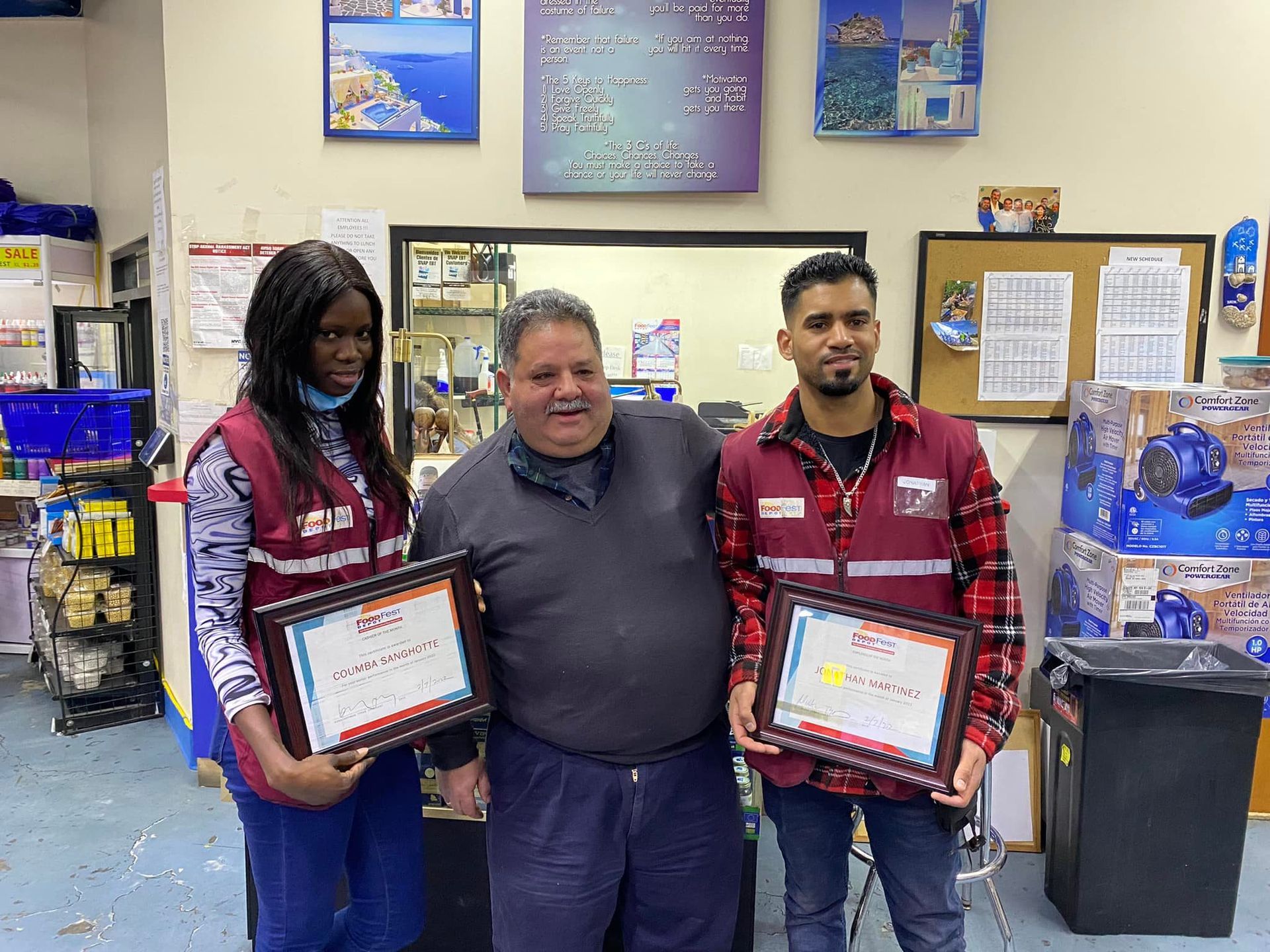 Three people are standing next to each other in a room holding certificates.