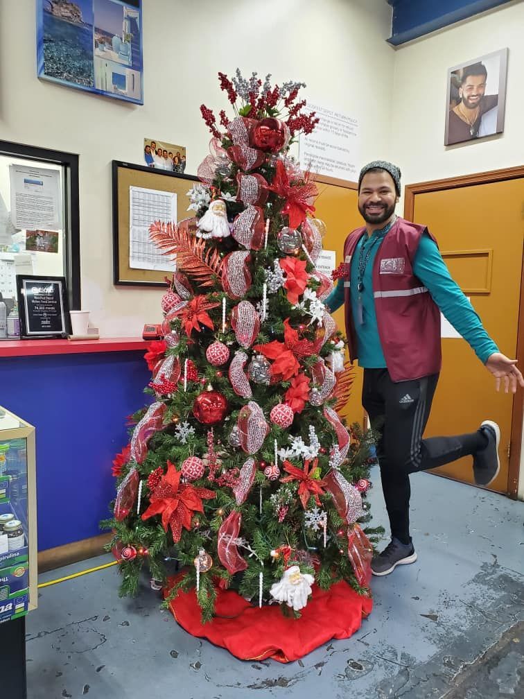 A man is standing next to a decorated christmas tree in a store.