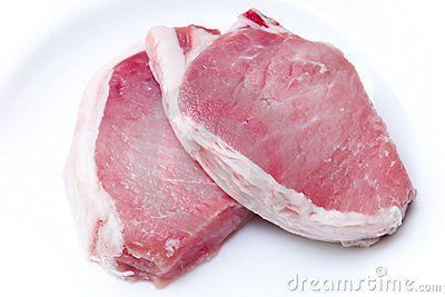 Two raw pork chops are on a white plate