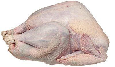 A raw turkey is laying on a white surface.