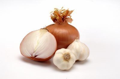 An onion and garlic are on a white surface