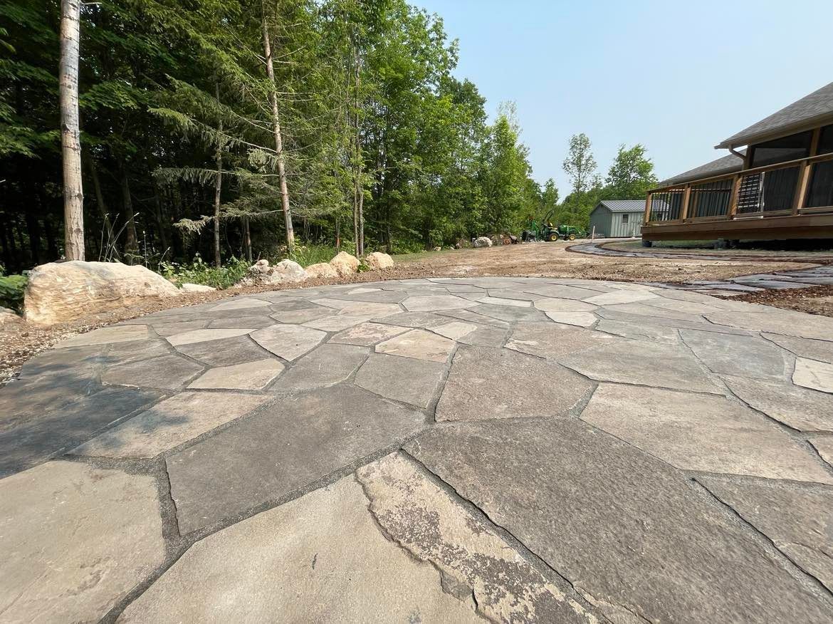 Stone path leading towards trees and a deck.