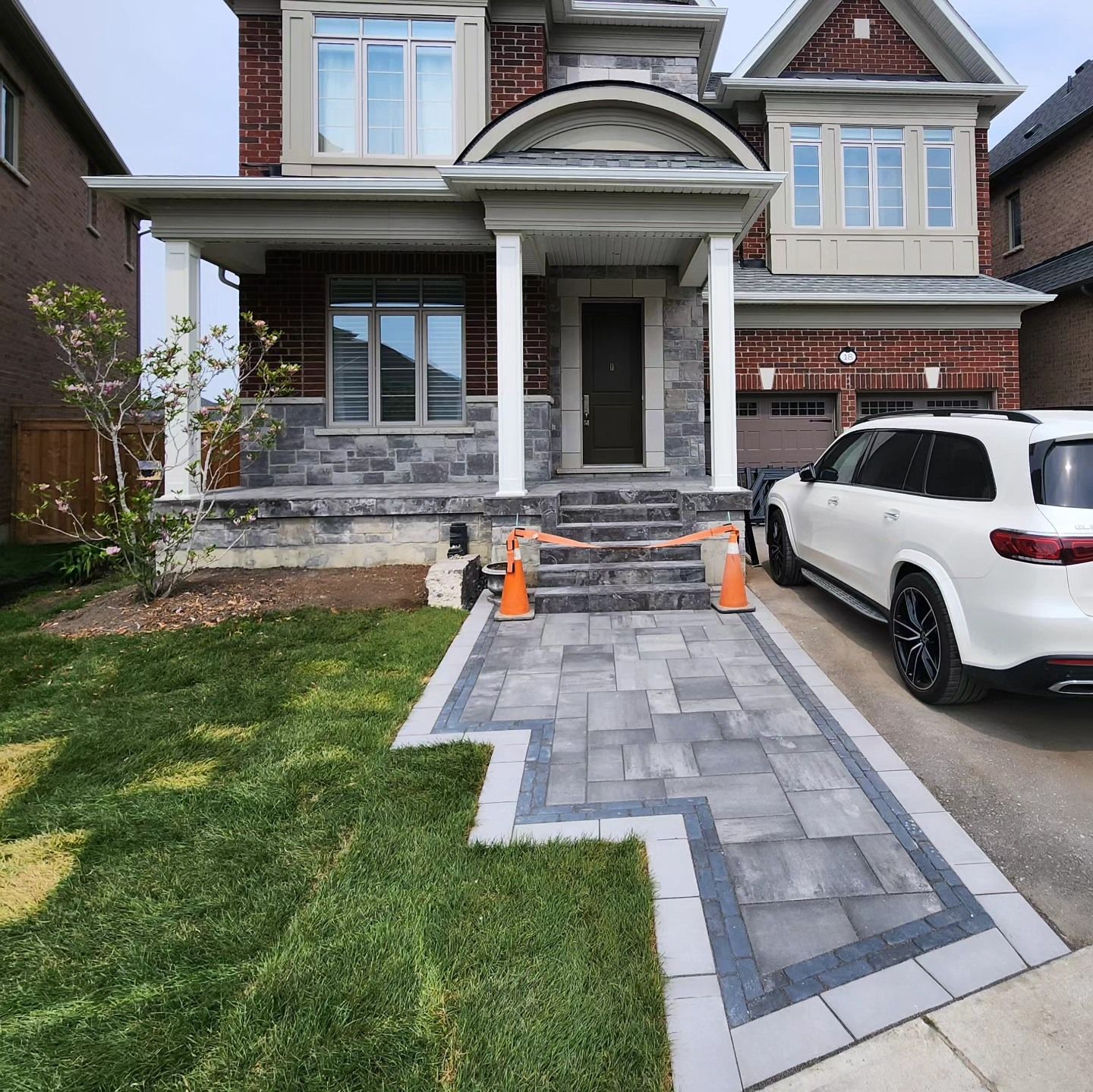 A white suv is parked in front of a brick house