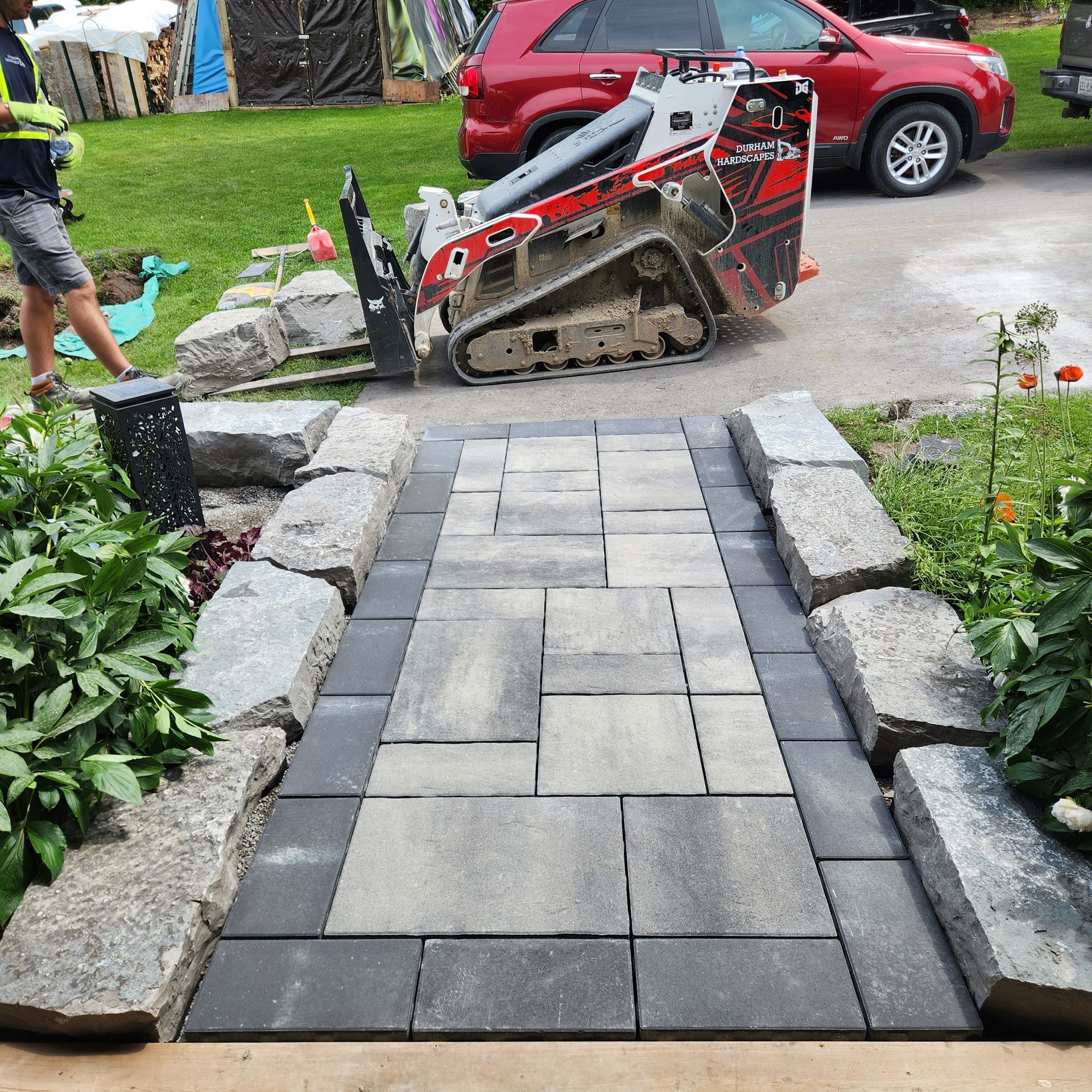 A red suv is parked next to a brick walkway