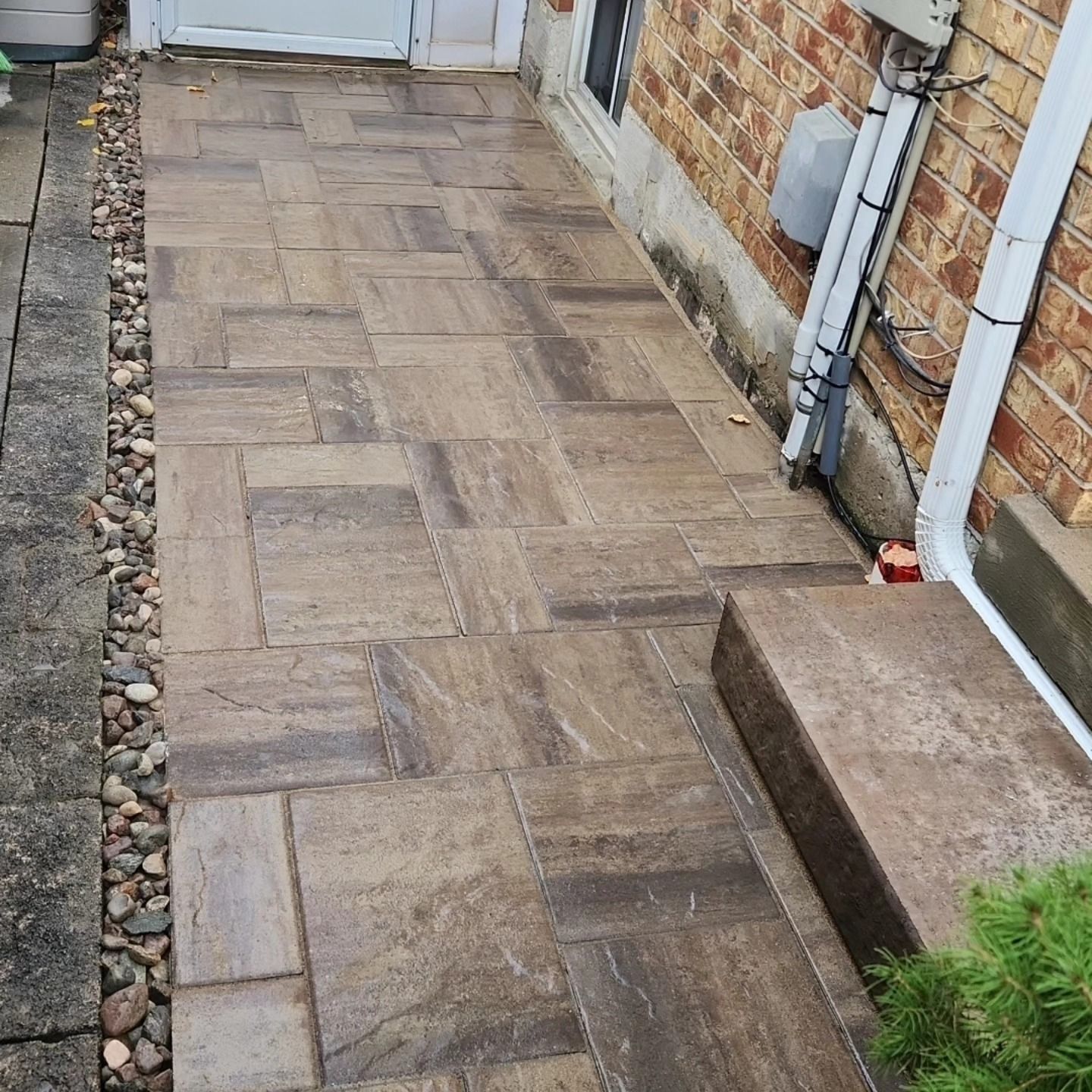 A sidewalk with steps leading to a brick building.