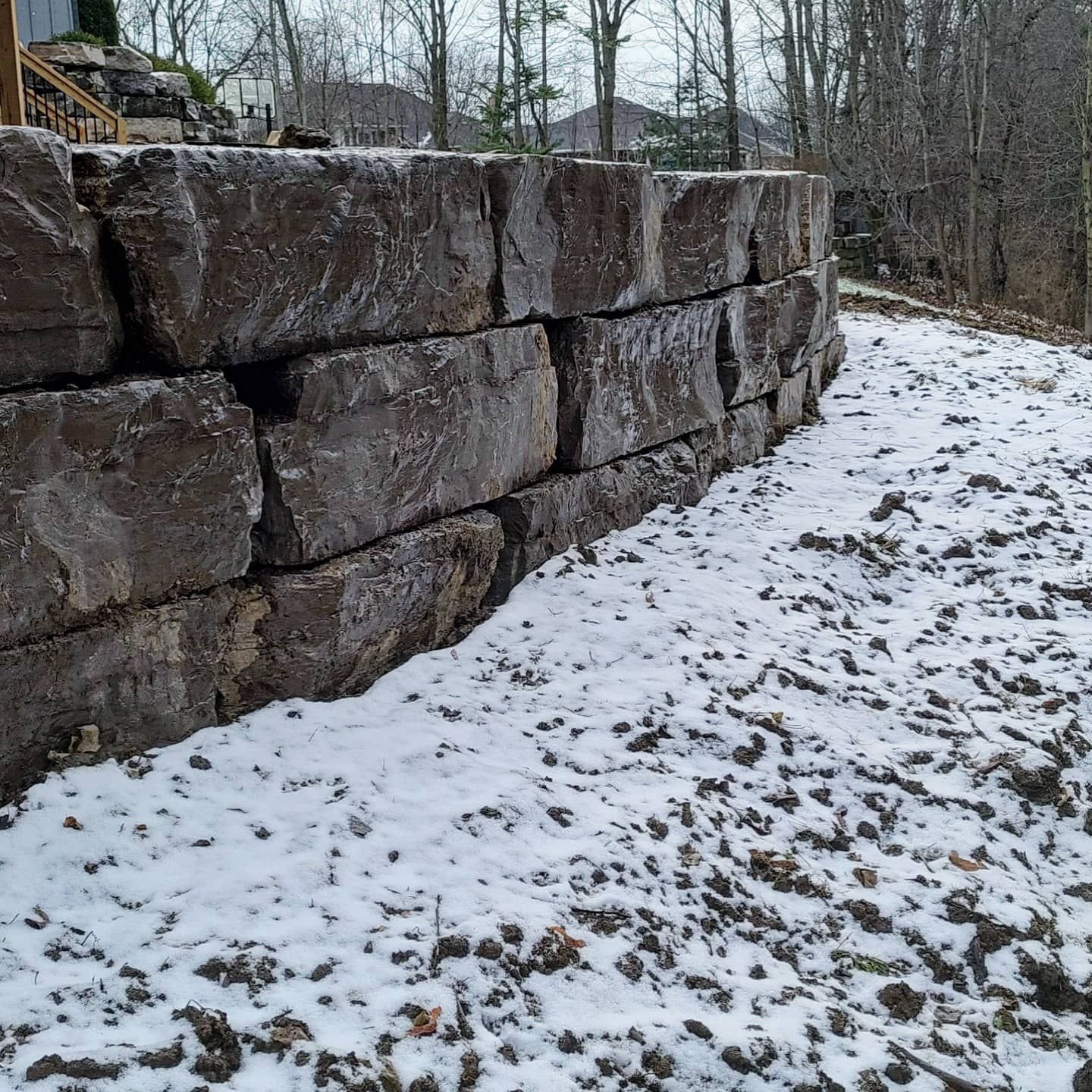 A stone wall with snow on the ground in front of it