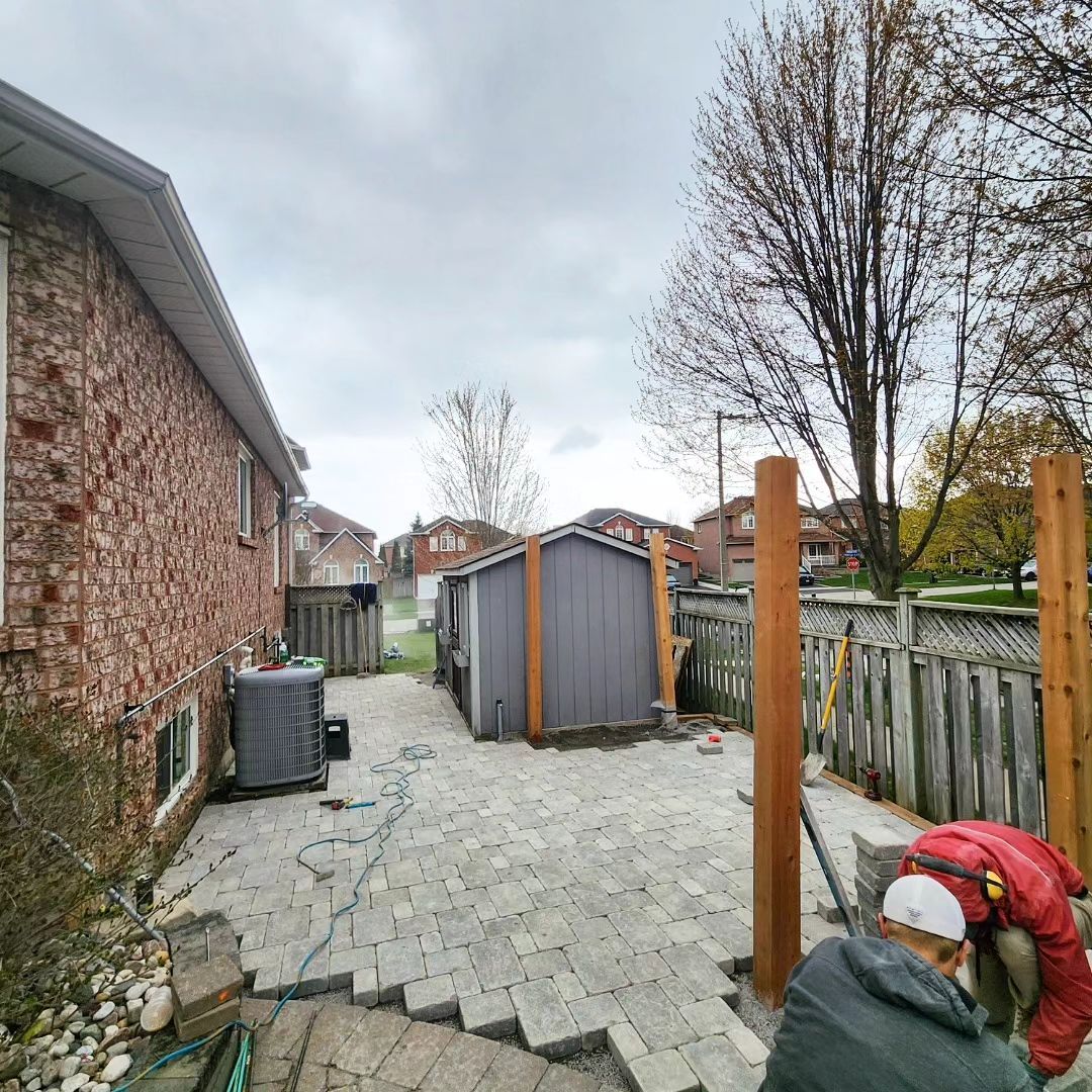 A man is working on a patio in front of a house.