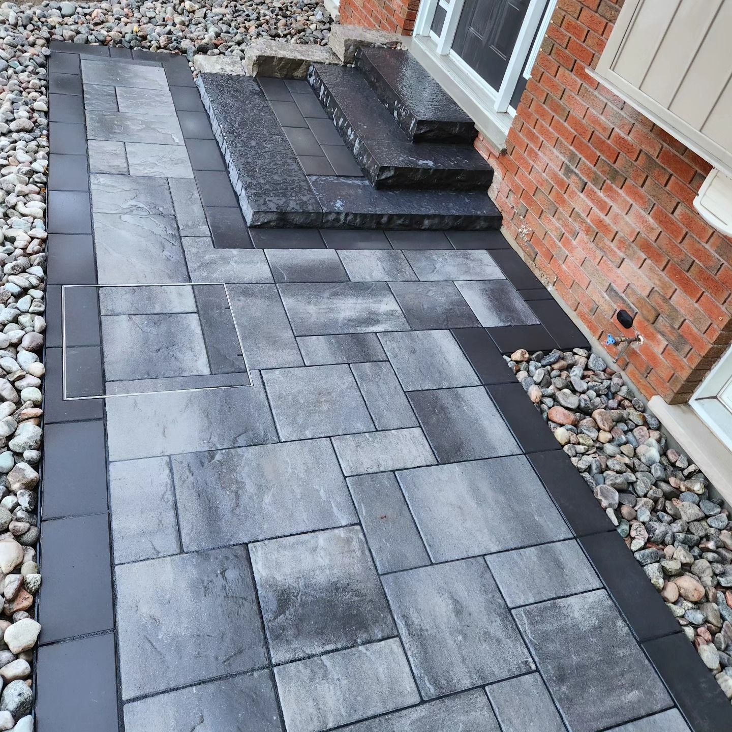 A stone walkway with steps leading to a brick house.
