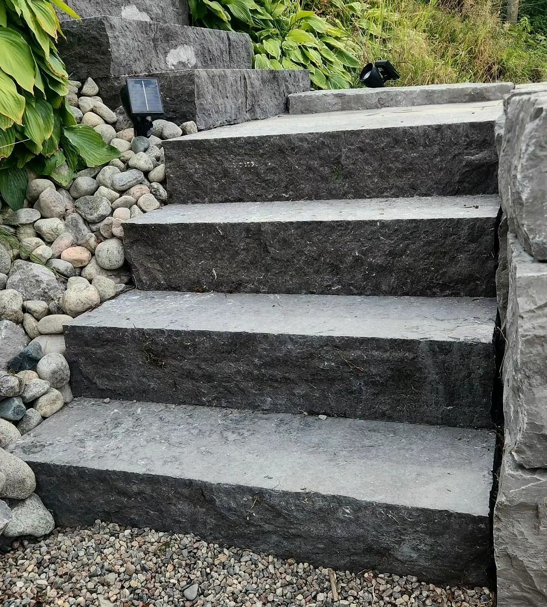 A set of stone stairs surrounded by rocks and gravel.