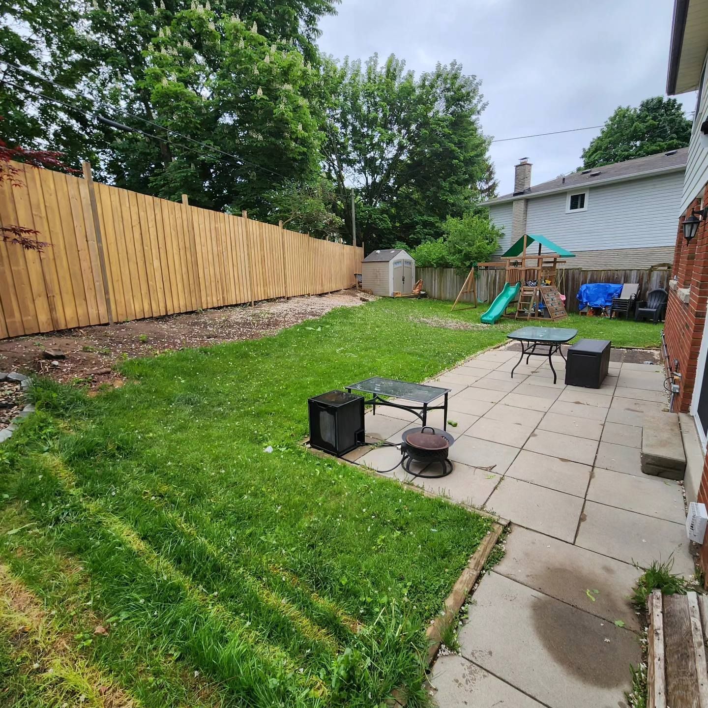 A backyard with a wooden fence and a patio