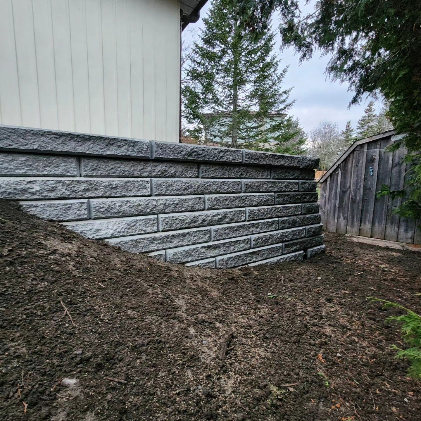 A brick wall is being built in the backyard of a house.