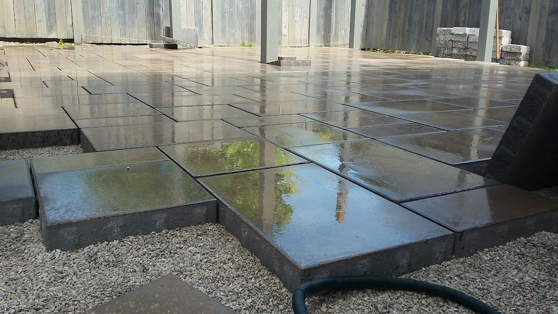 Wet gray paving stones being installed outdoors.