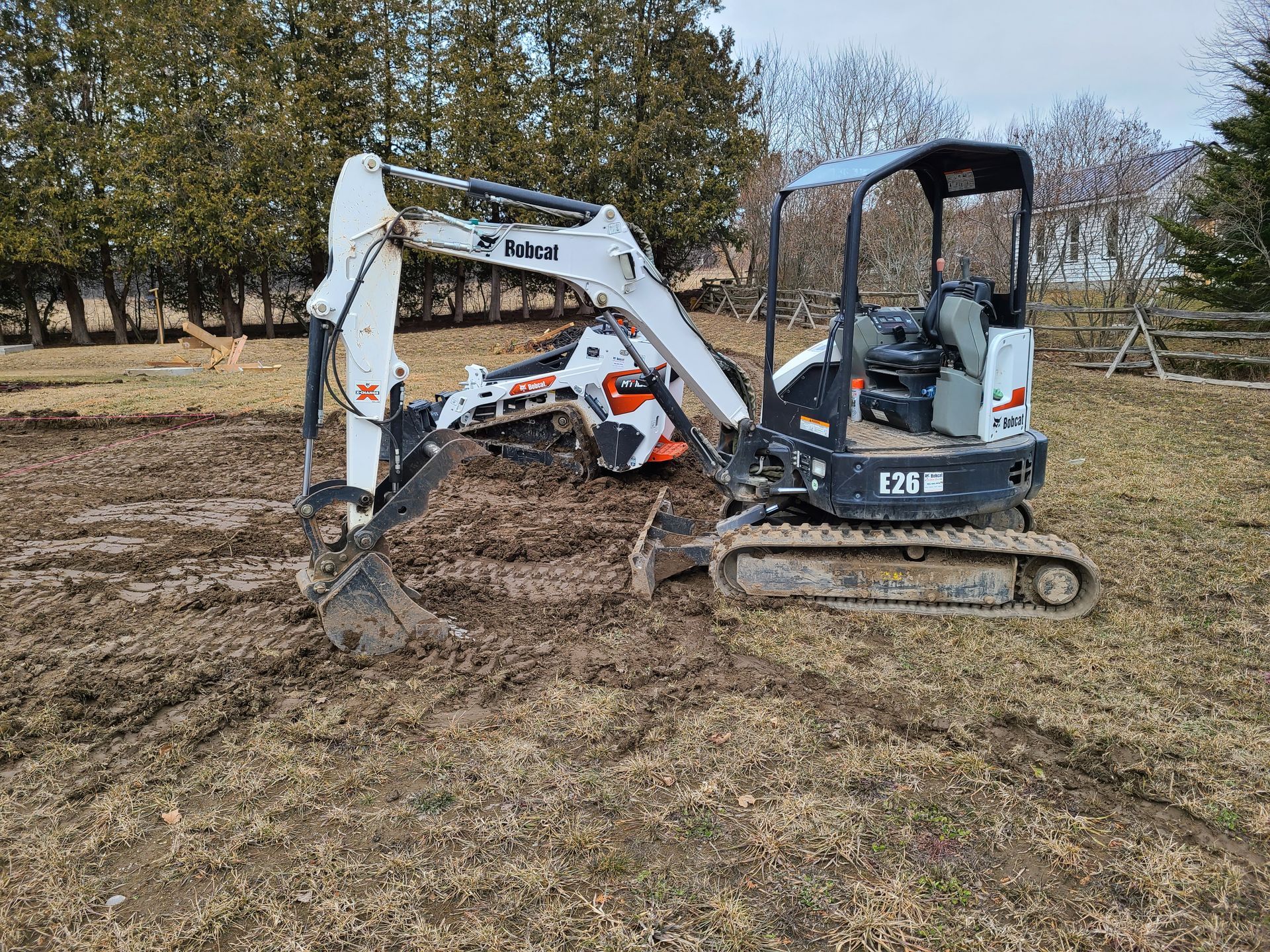 A small excavator is sitting in the middle of a muddy field.