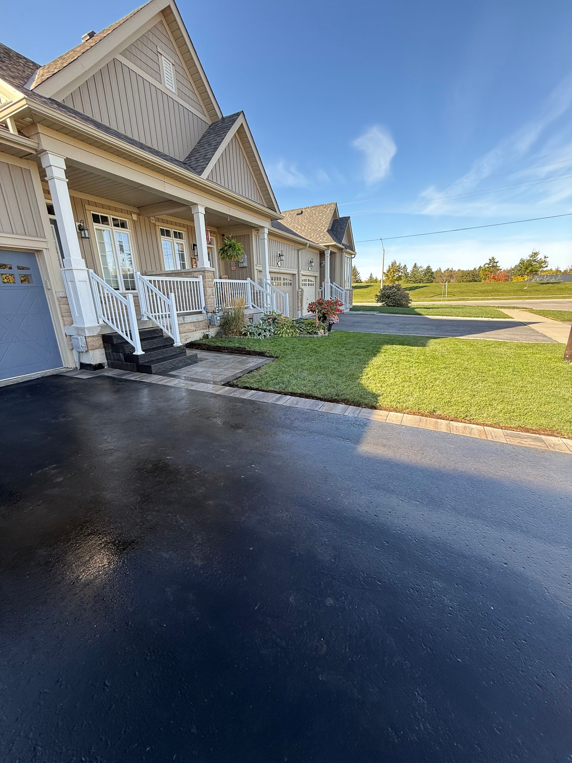 A house with a porch and a driveway on a sunny day.