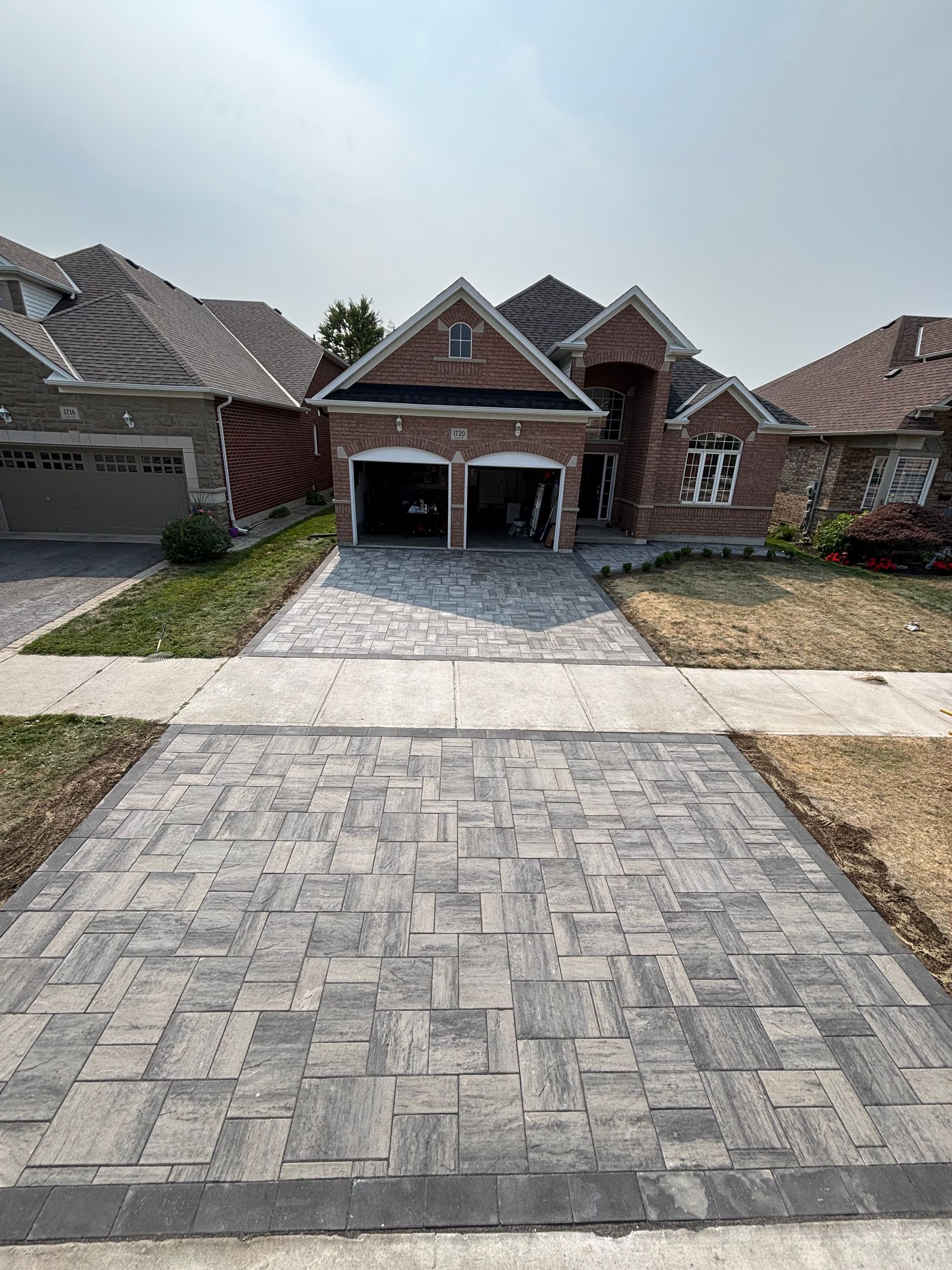 Brick house with paved driveway; two-car garage. Overcast sky.