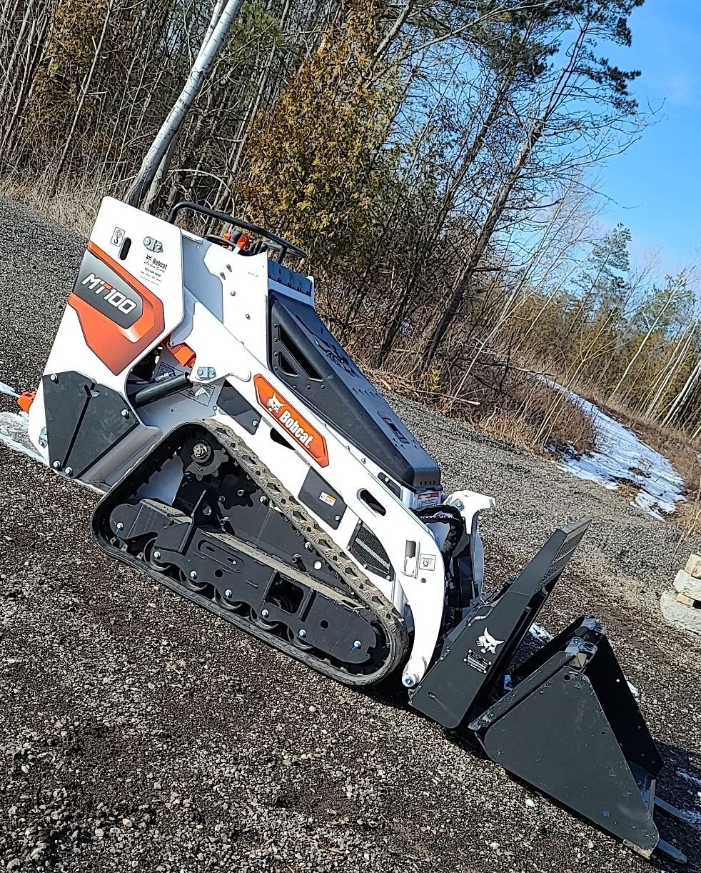 A small bulldozer is sitting on top of a gravel road.