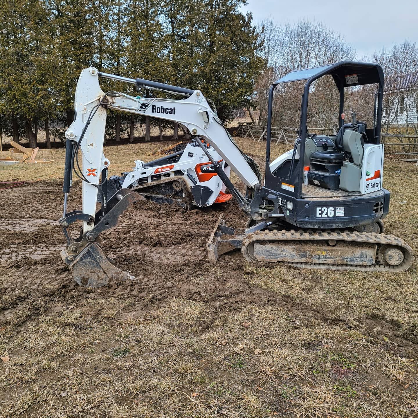 A small excavator is sitting in the middle of a muddy field.