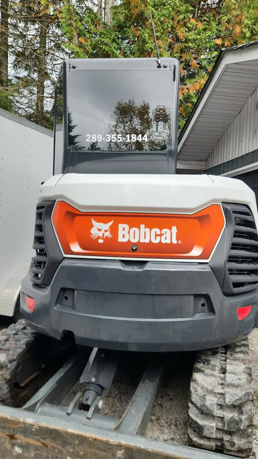 A bobcat excavator is parked in front of a house.