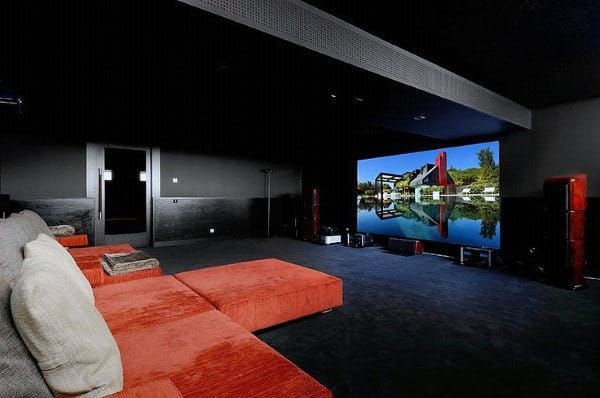 A home theater with an orange couch and a large screen