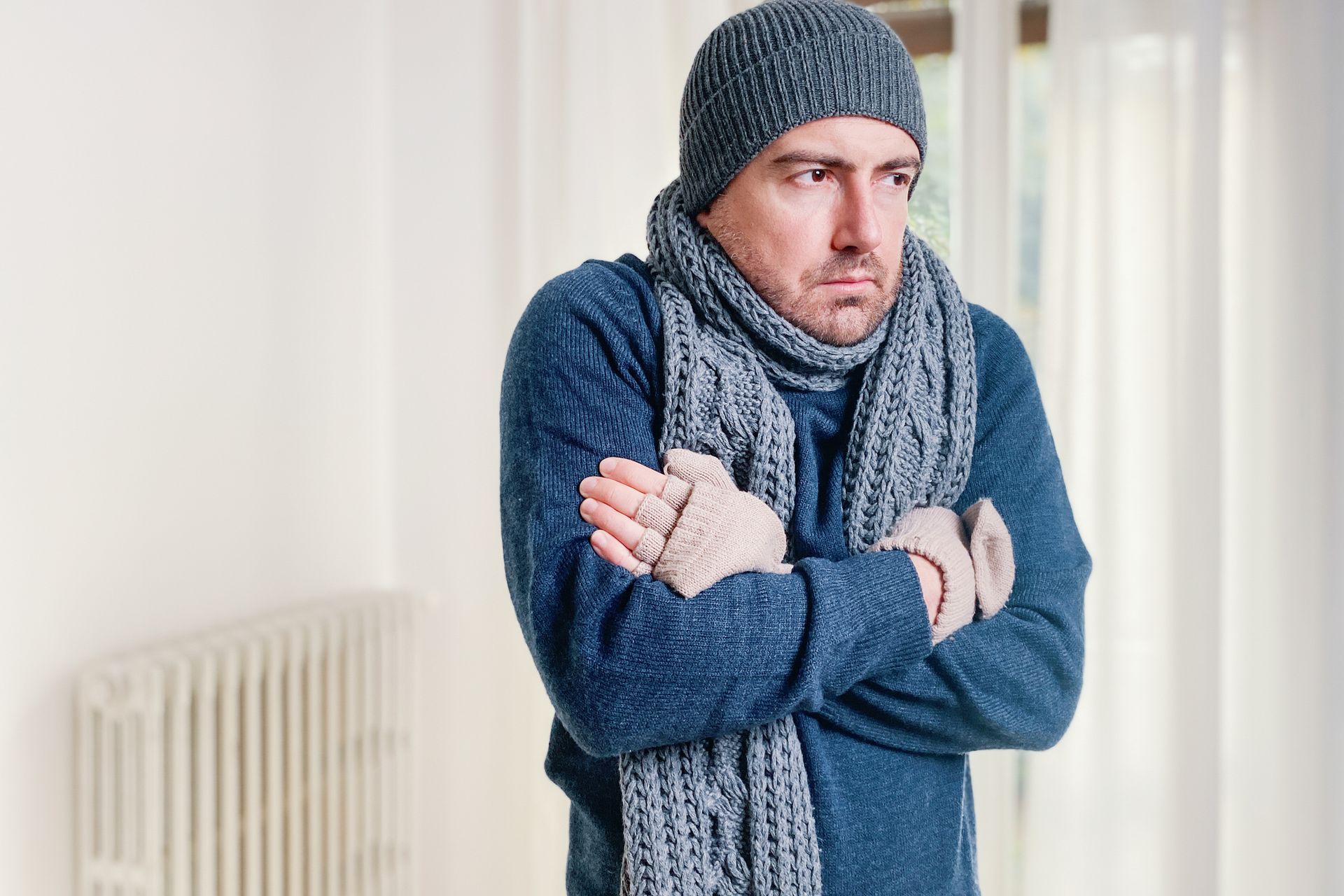 A man feeling cold at home needs furnace maintenance in a Cinnaminson home during winter.