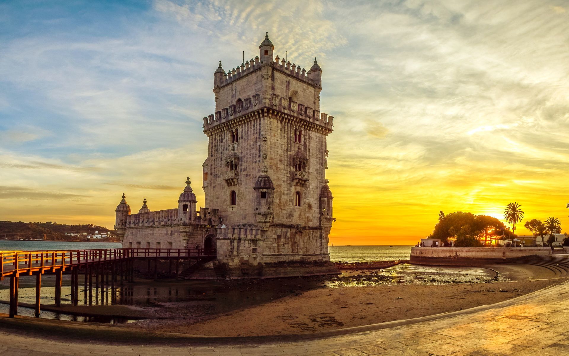 Belém Tower in Lisbon, Portugal, illuminated by a warm golden sunset on the shore of the Tagus River.