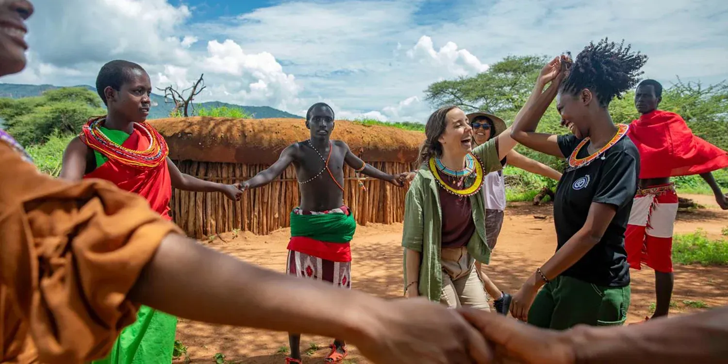 People holding hands and dancing in a circle outdoors.