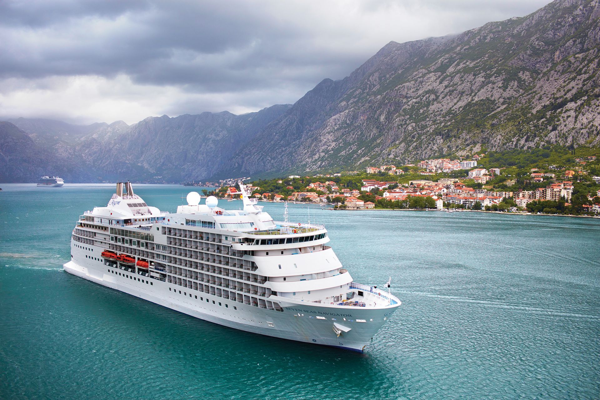 A cruise ship is floating in the ocean with mountains in the background