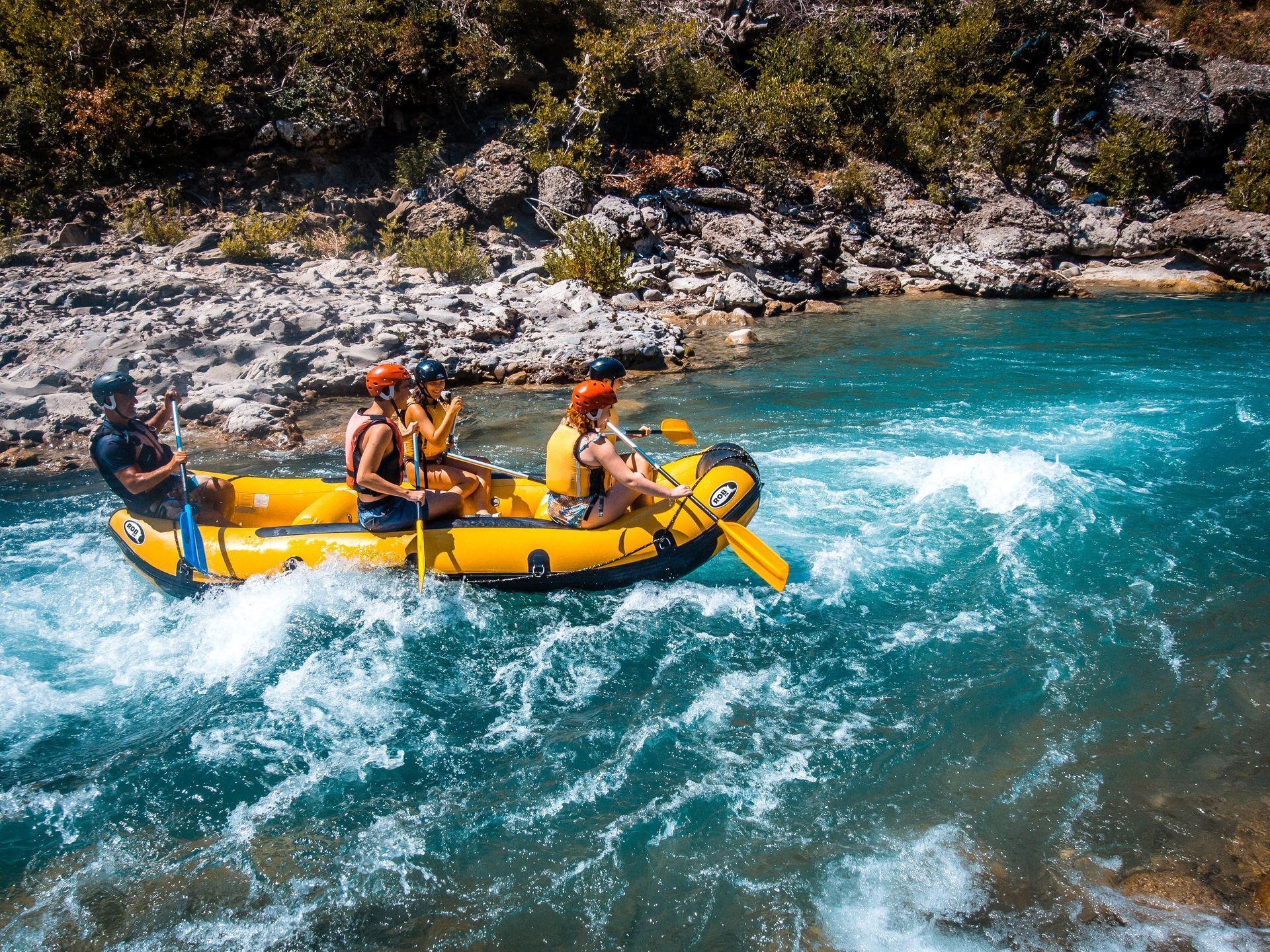 A group of people are rafting down a river in a yellow raft