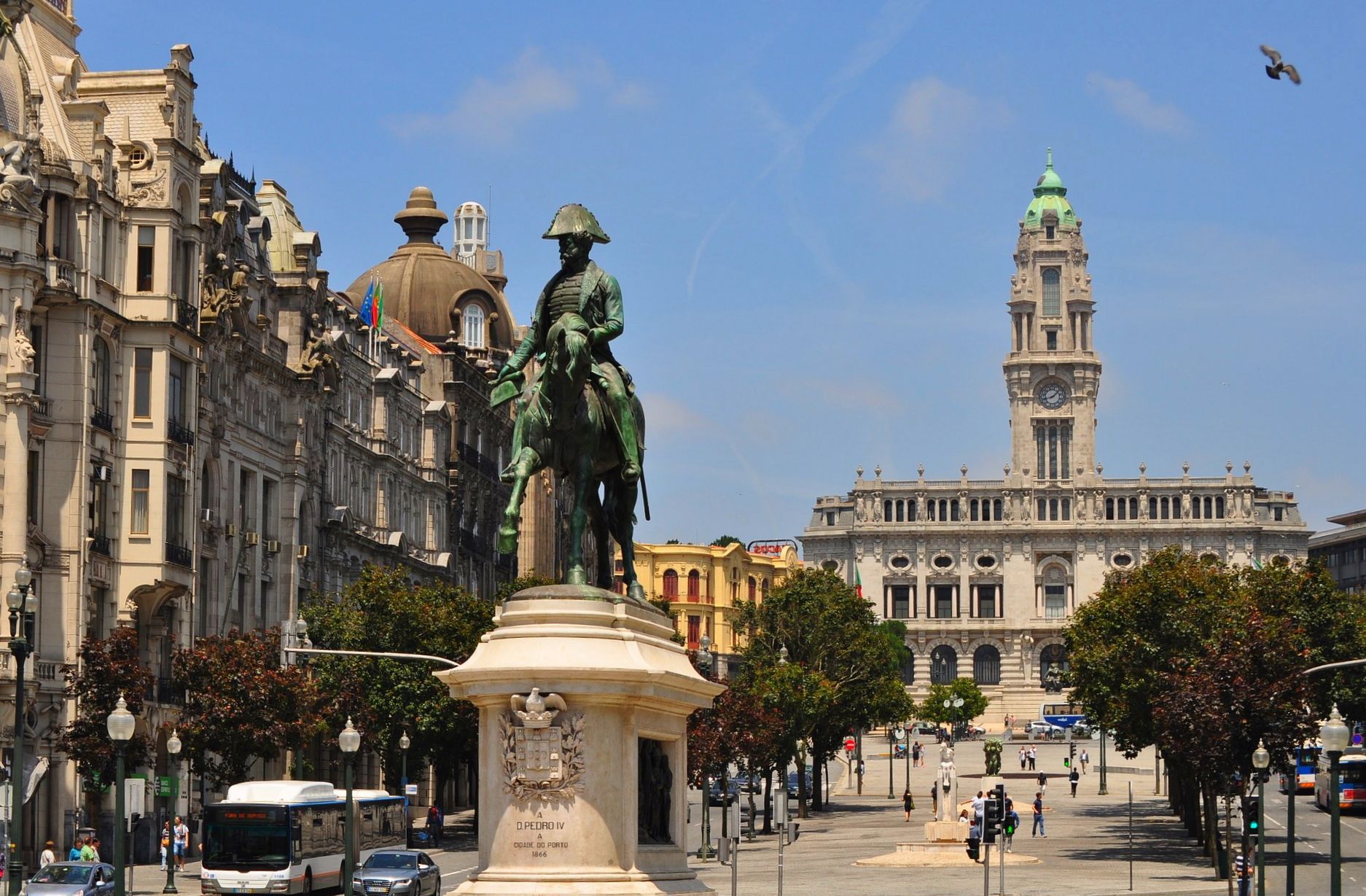 A bronze equestrian statue stands in a sunny plaza in Porto, Portugal, with the Town Hall building in the background.