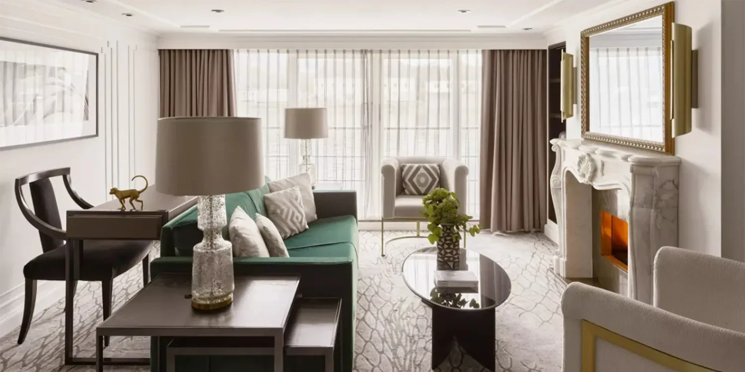 Living room with green couch, fireplace, mirror, and two dark chairs.