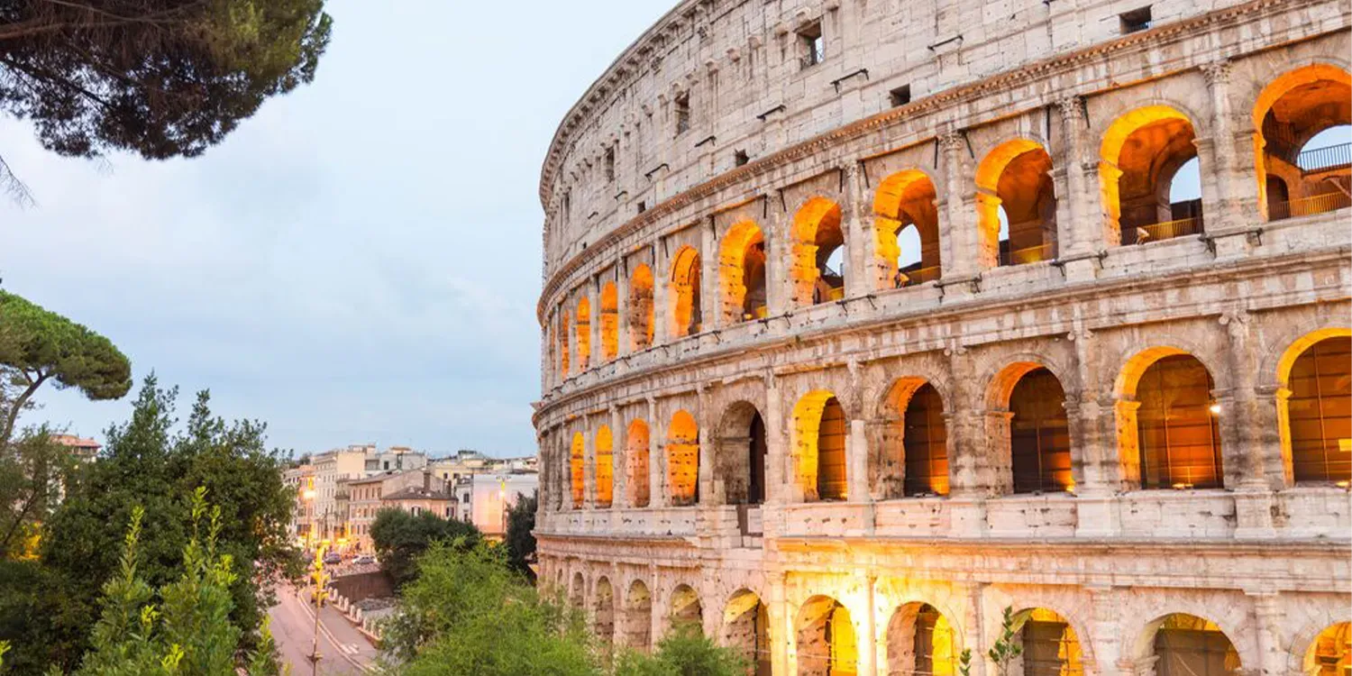 Colosseum in Rome, Italy, at dusk, with illuminated archways.