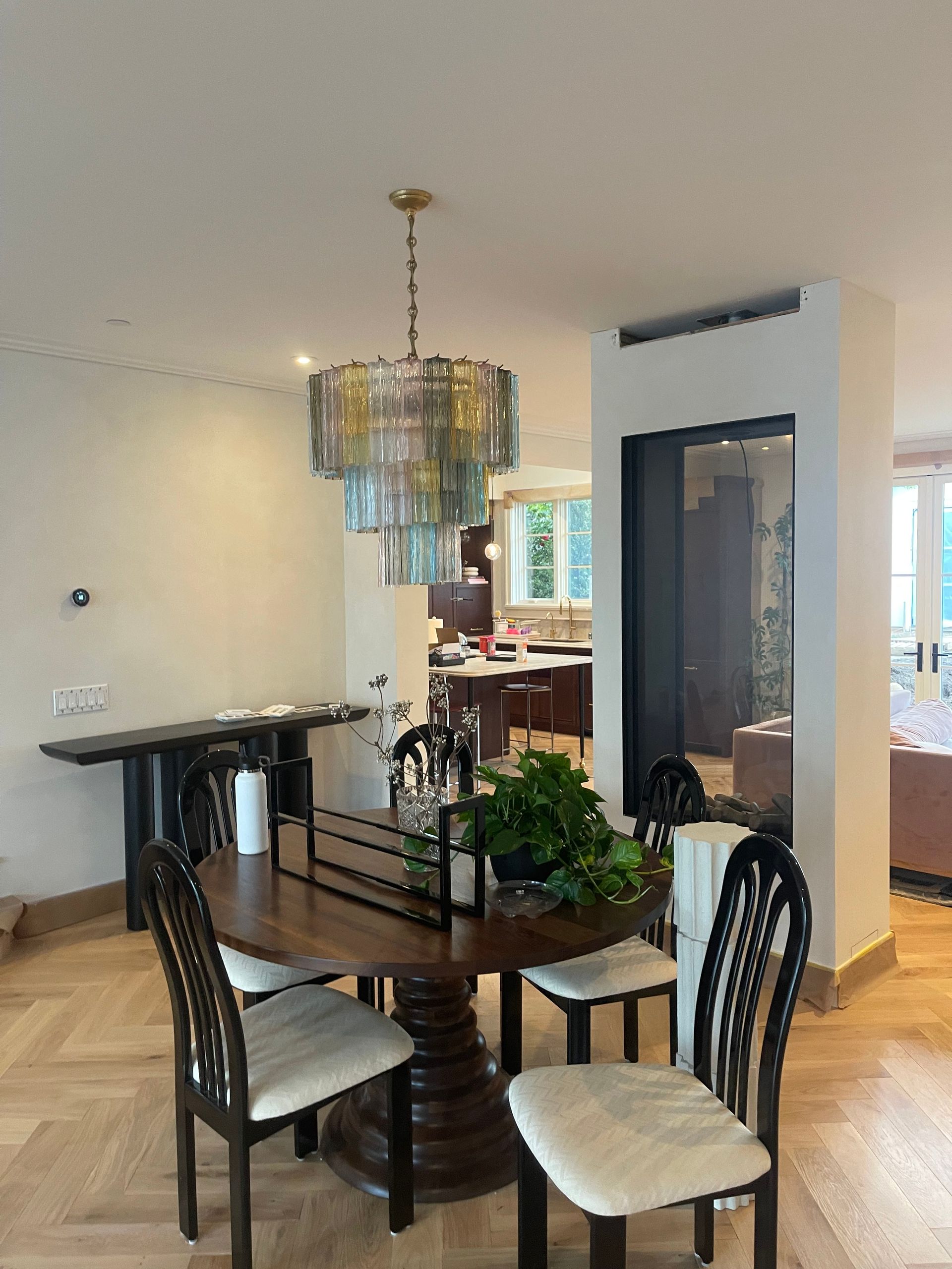 A dining room with a table and chairs and a chandelier hanging from the ceiling.