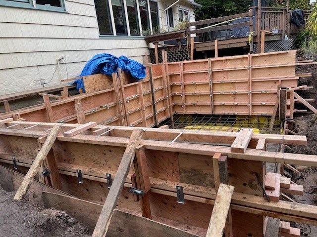 A wooden wall is being built in front of a house.
