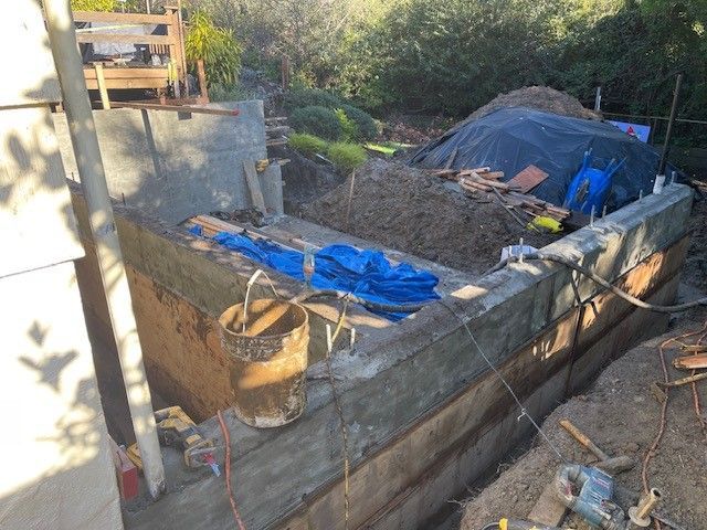 A large pile of dirt is sitting on top of a concrete wall.
