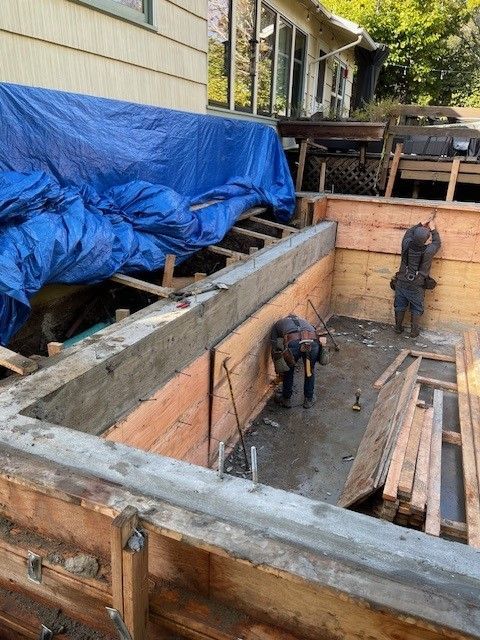 A man is working on a concrete wall in front of a house.
