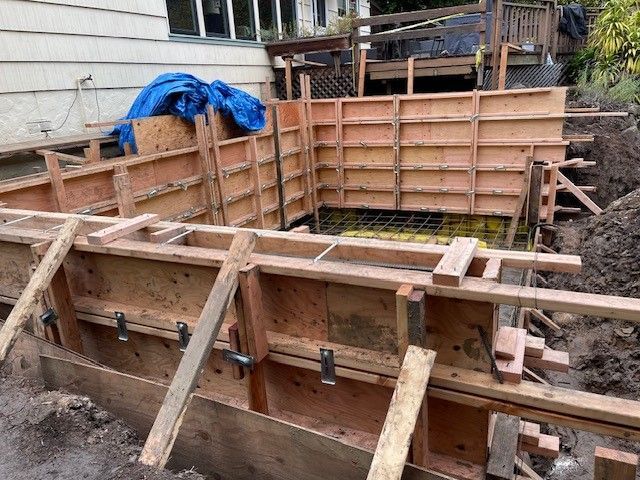 A wooden wall is being built in front of a house.