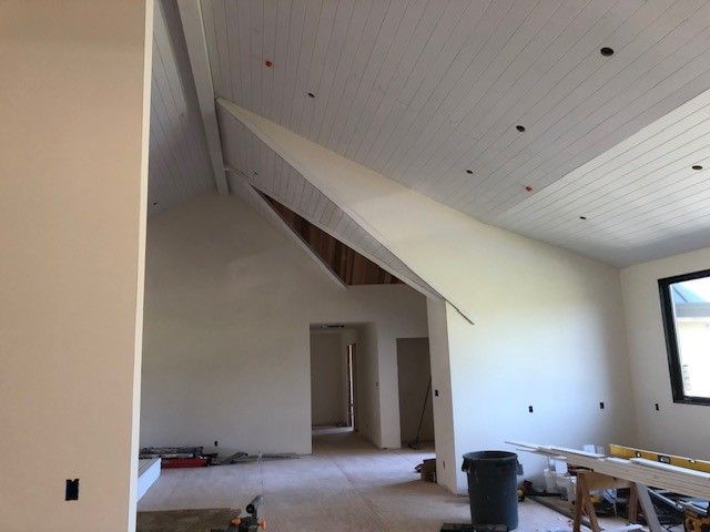 A large empty room with a vaulted ceiling and a window.