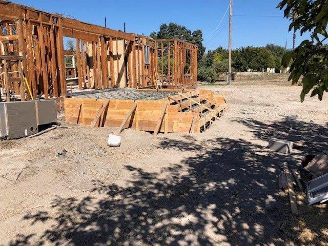 A house is being built in the middle of a dirt field.